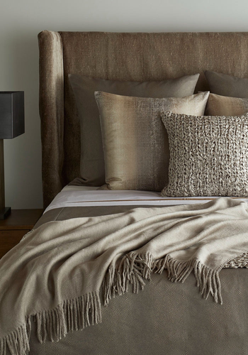 Neatly made bed with textured pillows and a blanket in a bedroom setting.3