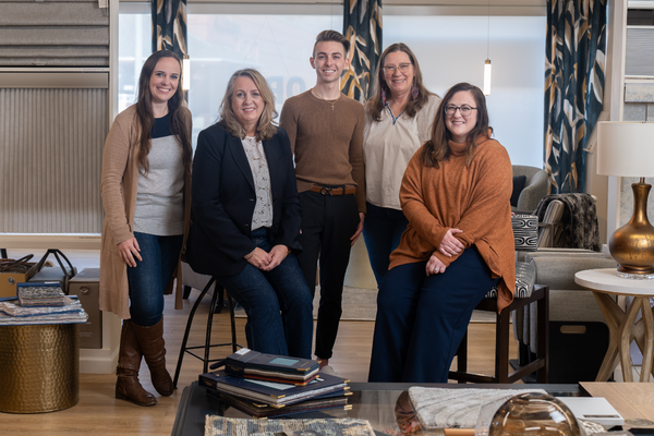 Group of five people in a home decor store with samples and furniture.