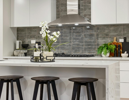Modern kitchen with white cabinets, gray backsplash, and black stovetop.