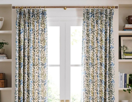 Decorative curtains with a floral pattern hanging in front of a window.