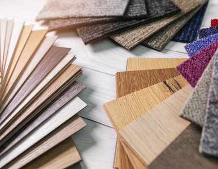 Collection of wood, carpet, and vinyl flooring samples on a white surface