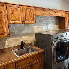 laundry room back splash with neutral porcelain tile and custom wood cabinetry