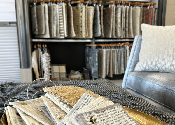 carpet swatches on a table with a chair and more rug samples in the background
