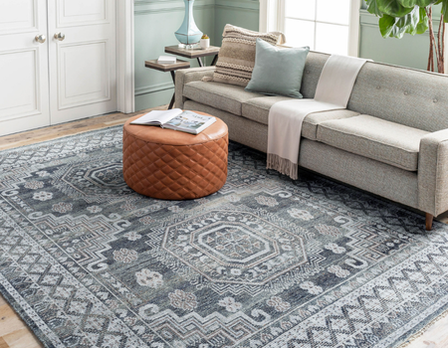 Living room with a sectional sofa, patterned rug, and ottoman.